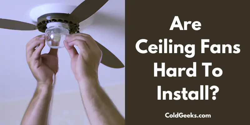 Man's arms installing a ceiling fan - are ceiling fans hard to install